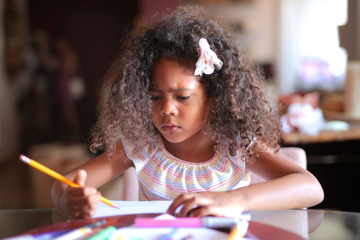 A child concentrating while writing with a pencil