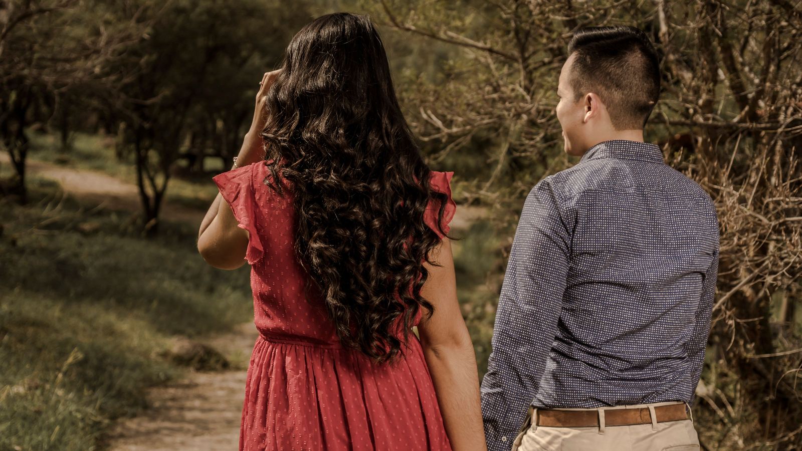 A couple holding hands while walking along a path outdoors