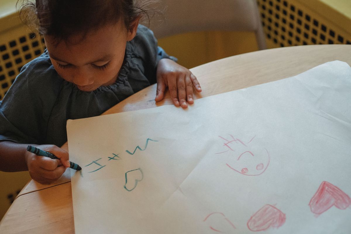 A child drawing on paper with wax crayons