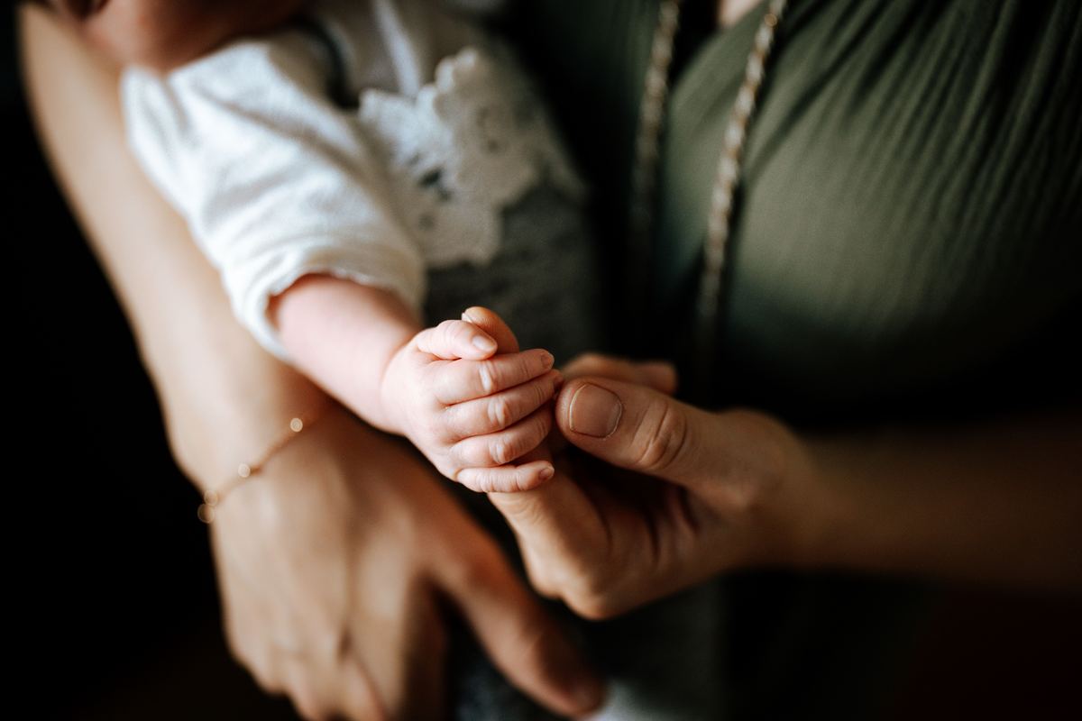 A close-up of an adult hand holding a baby's hand