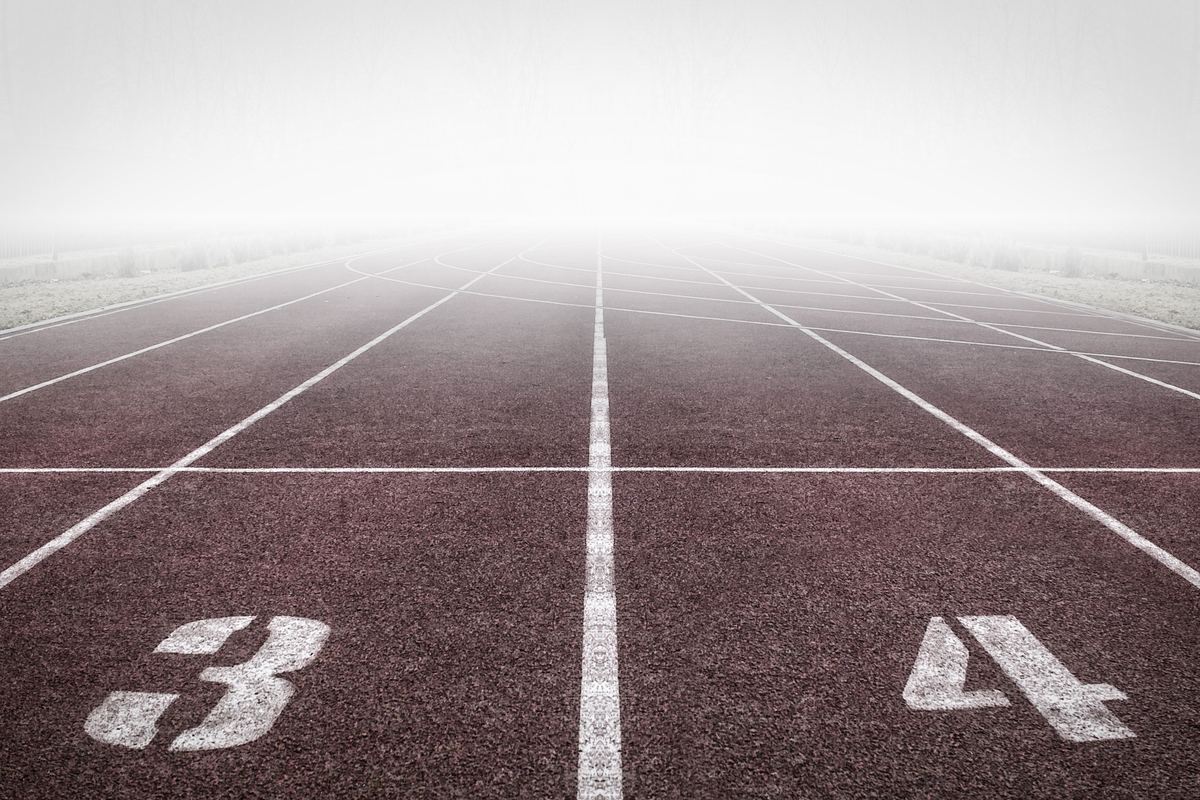 Numbered lanes on a running track in morning fog