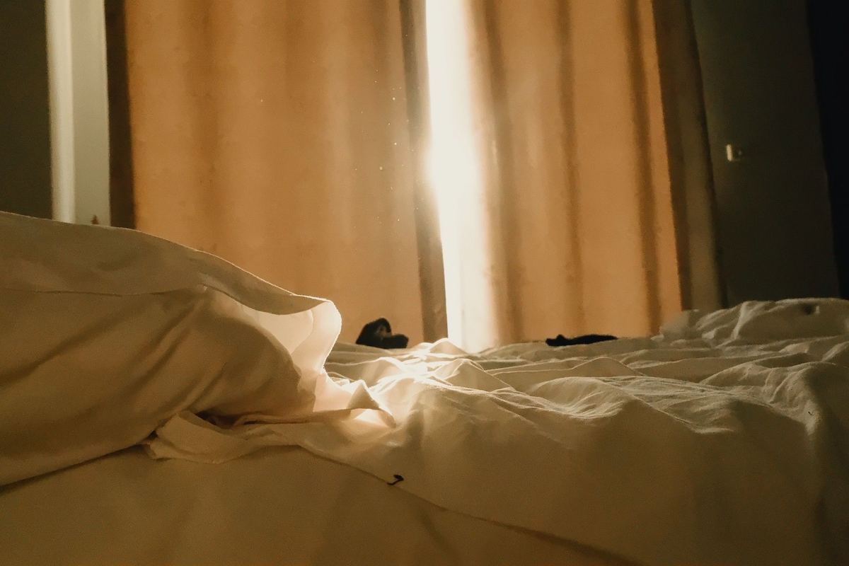Morning sunlight falling through curtains onto a bed