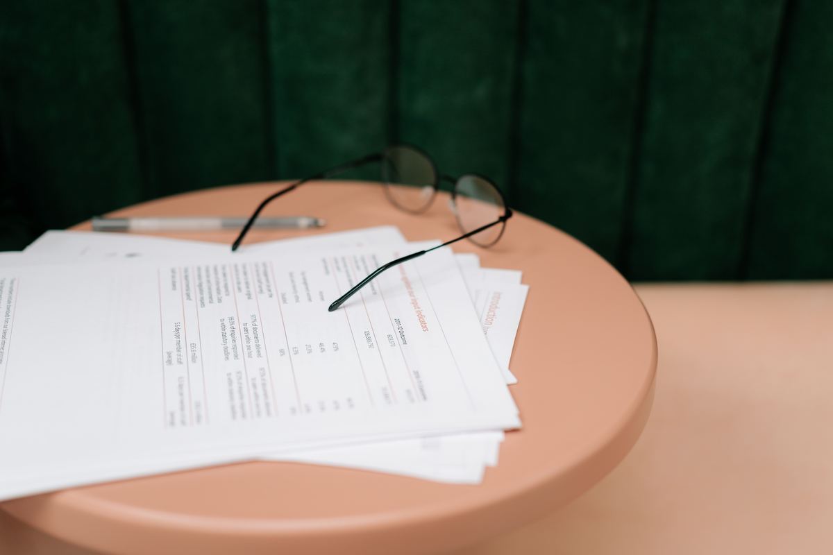 Documents, reading glasses and a pen on a table