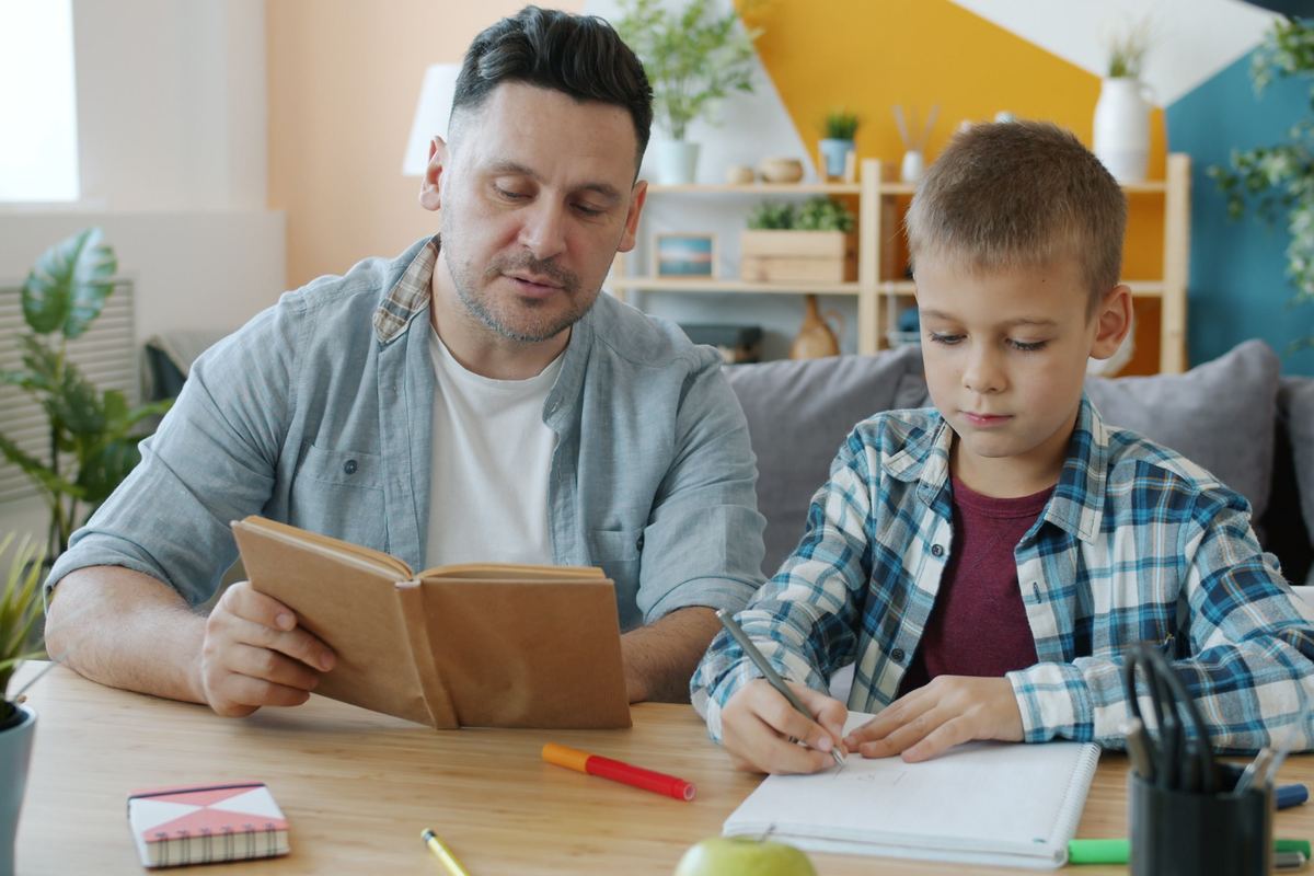 A parent sitting beside a child working through homework