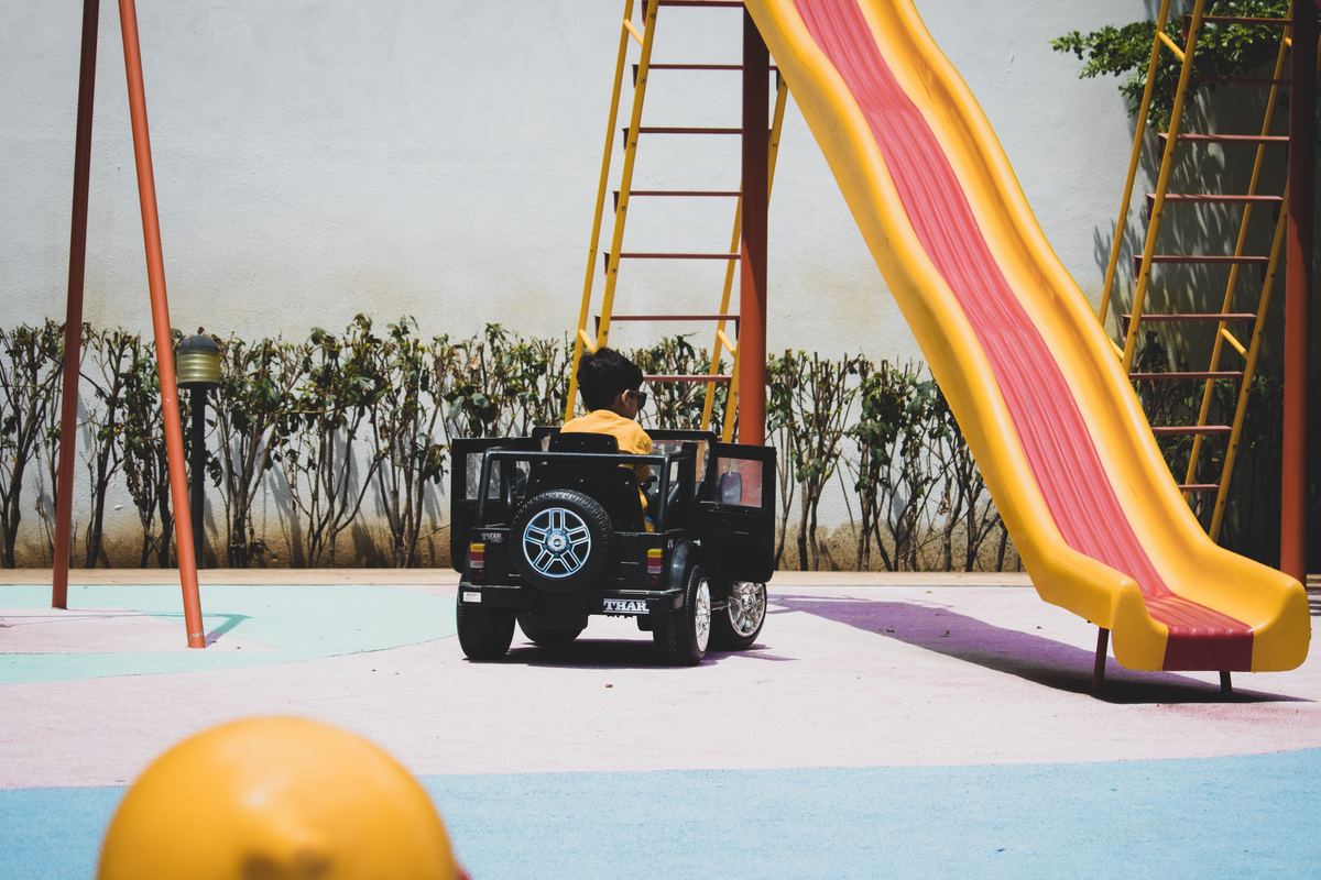 A child playing with a toy car beside a playground slide