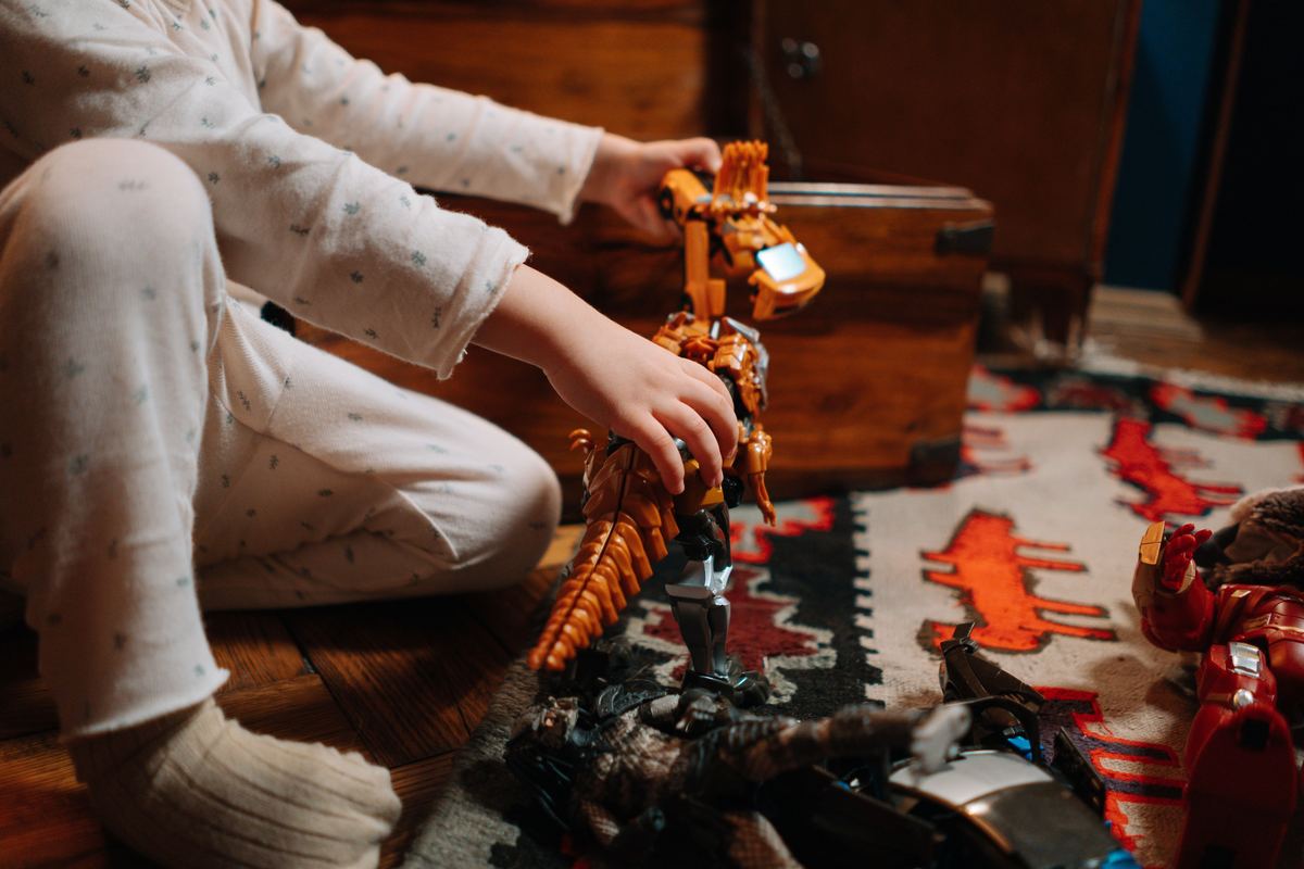 A child playing with a toy dinosaur on a rug