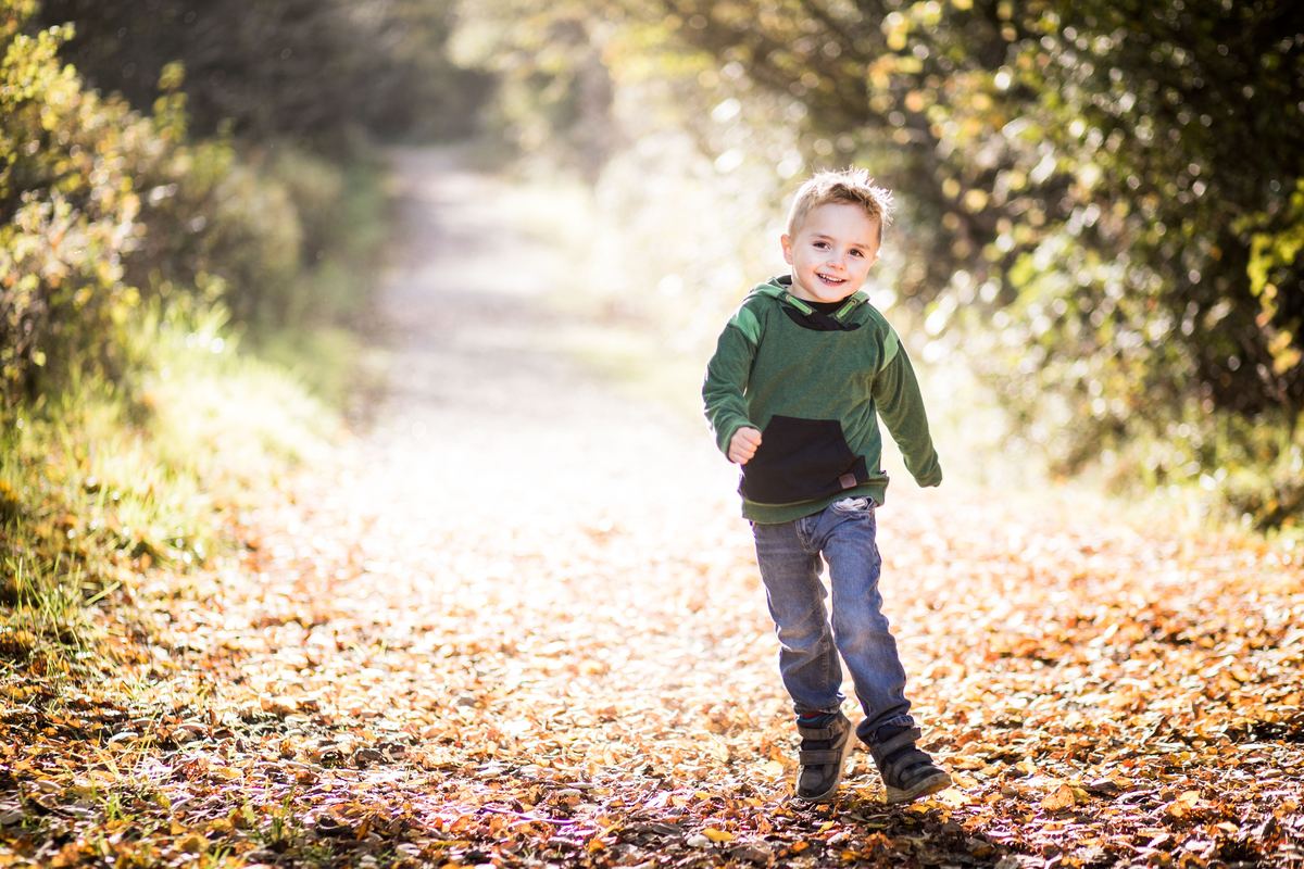 A child running along a leaf-covered path outdoors