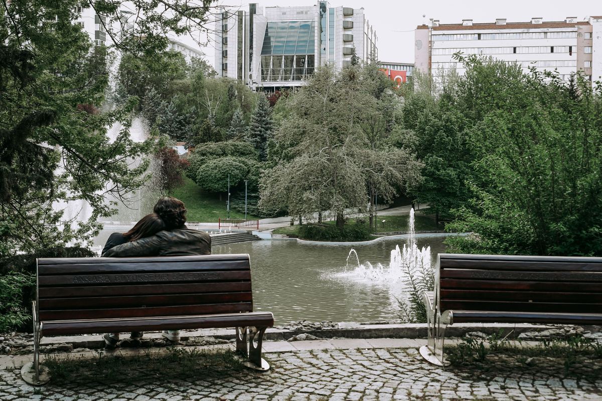 A couple sitting together on a bench beside a fountain