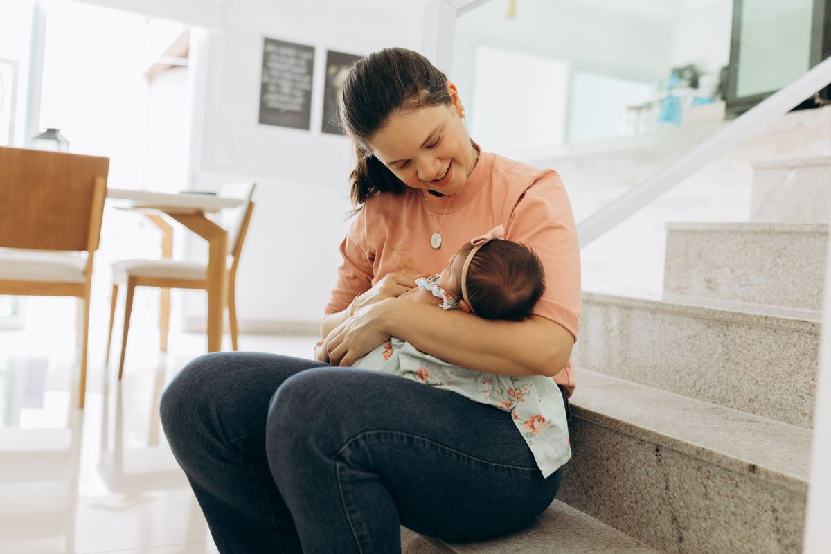 A parent smiling while cradling a baby indoors
