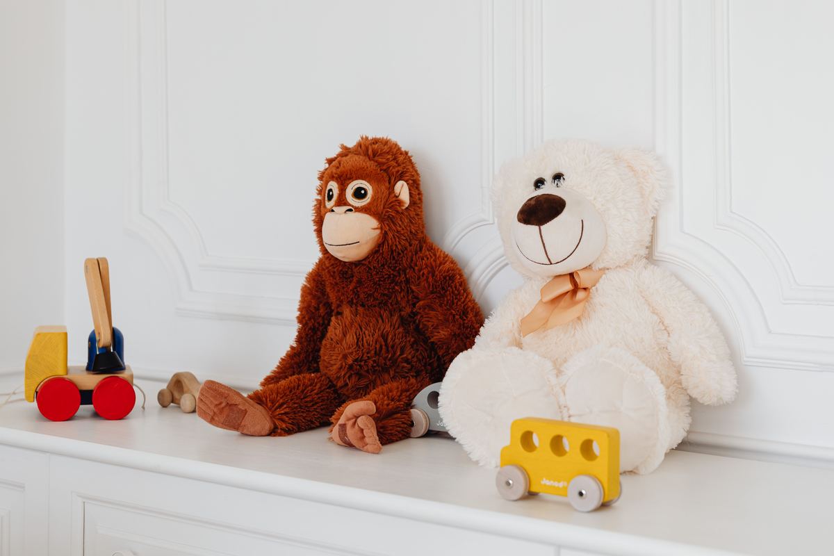 Plush toys and wooden cars arranged on a white shelf