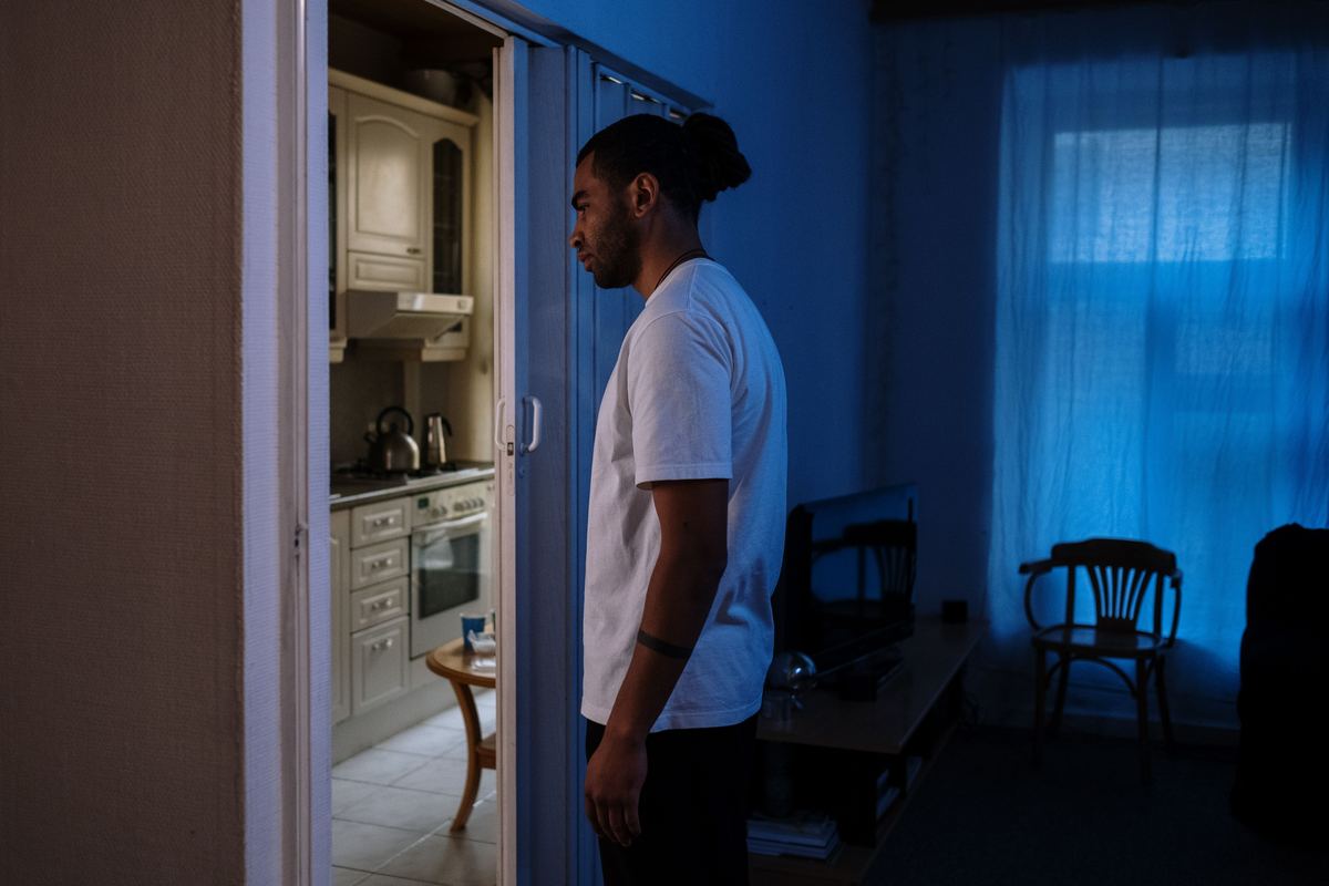 A person standing alone in a dimly lit room near a door
