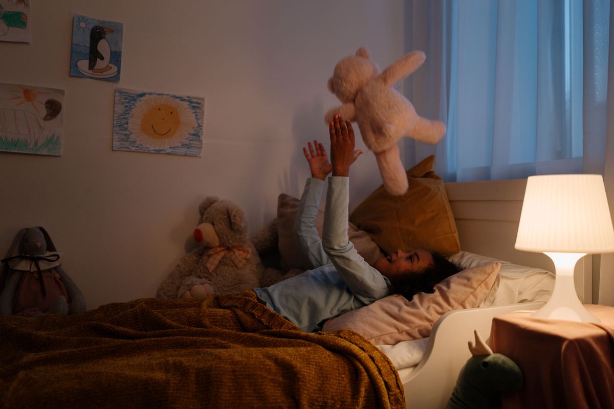 A child playing with a teddy bear in a bedroom at night