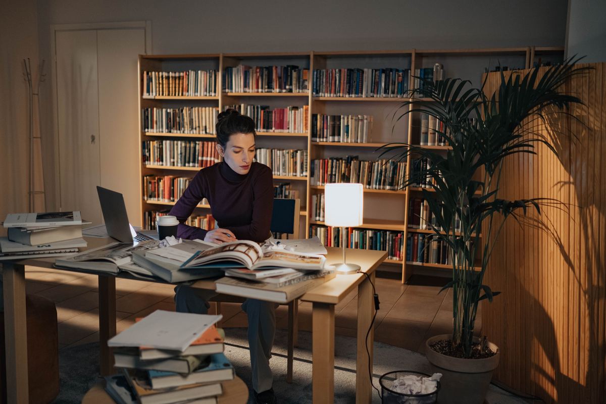 A student working at a library desk late in the evening