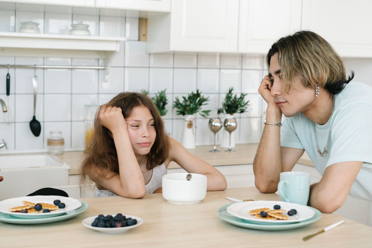 A parent and child talking over breakfast at a kitchen table