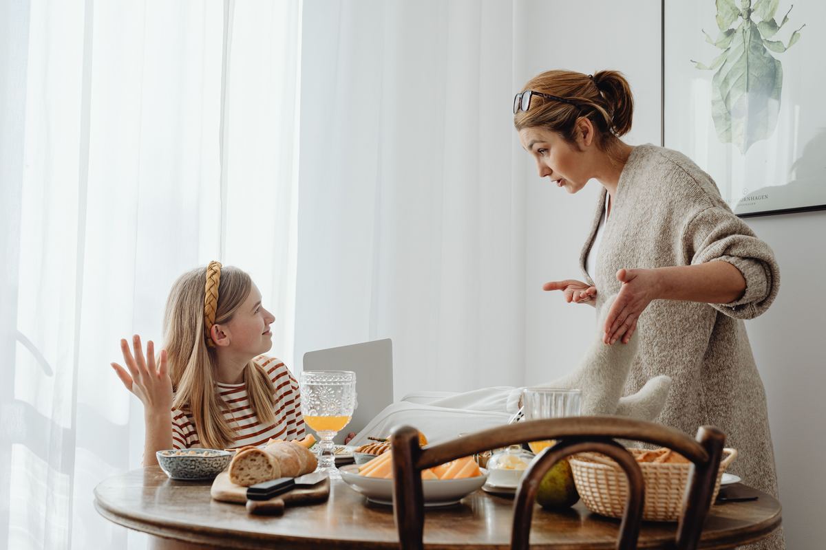A parent and teenager talking over breakfast at a kitchen table