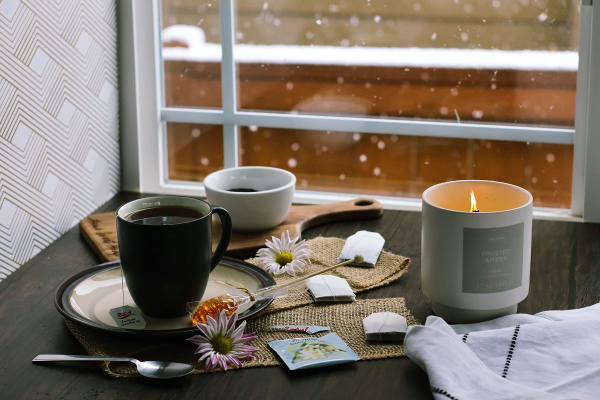 Tea, candles and flowers on a table beside a window