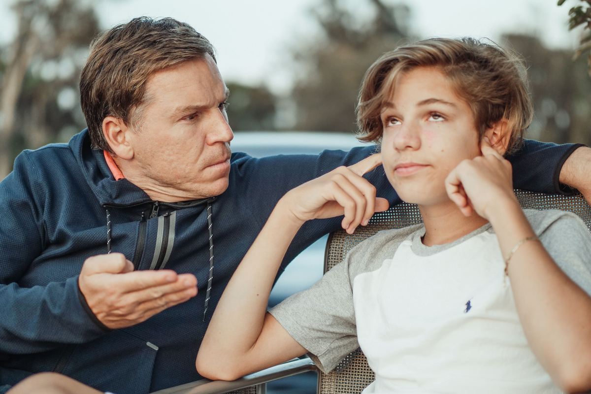 A parent and teenager in a car during a tense conversation