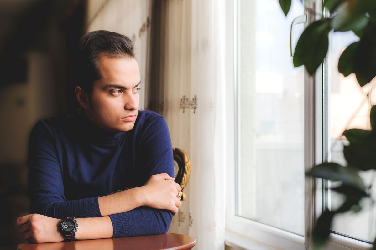 A person leaning on a table looking out of a window