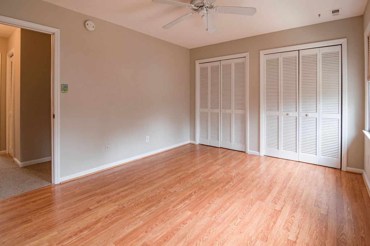 An empty room with hardwood floors and open closet doors