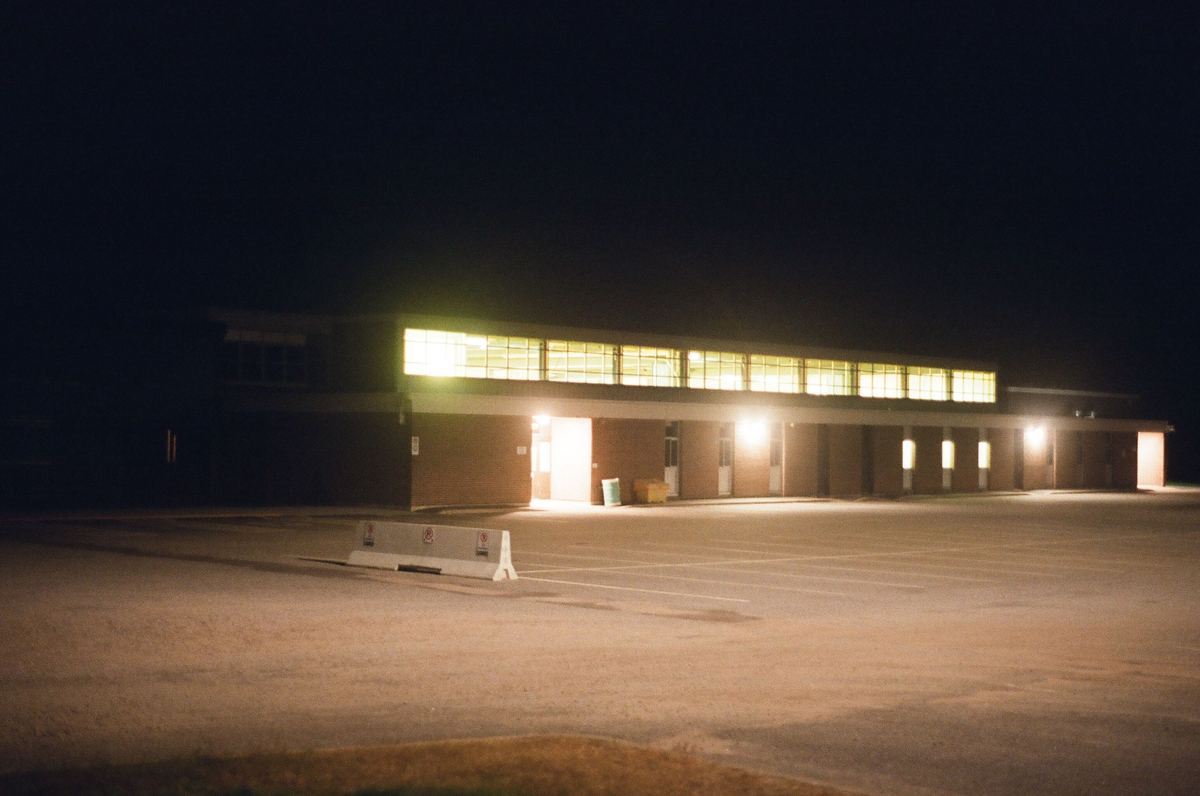 A dimly lit empty parking lot beside a school building at night
