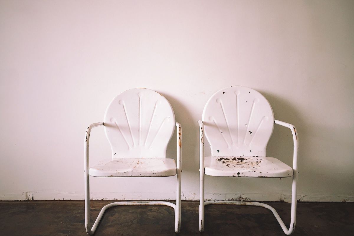 Two metal chairs side by side against a bare wall