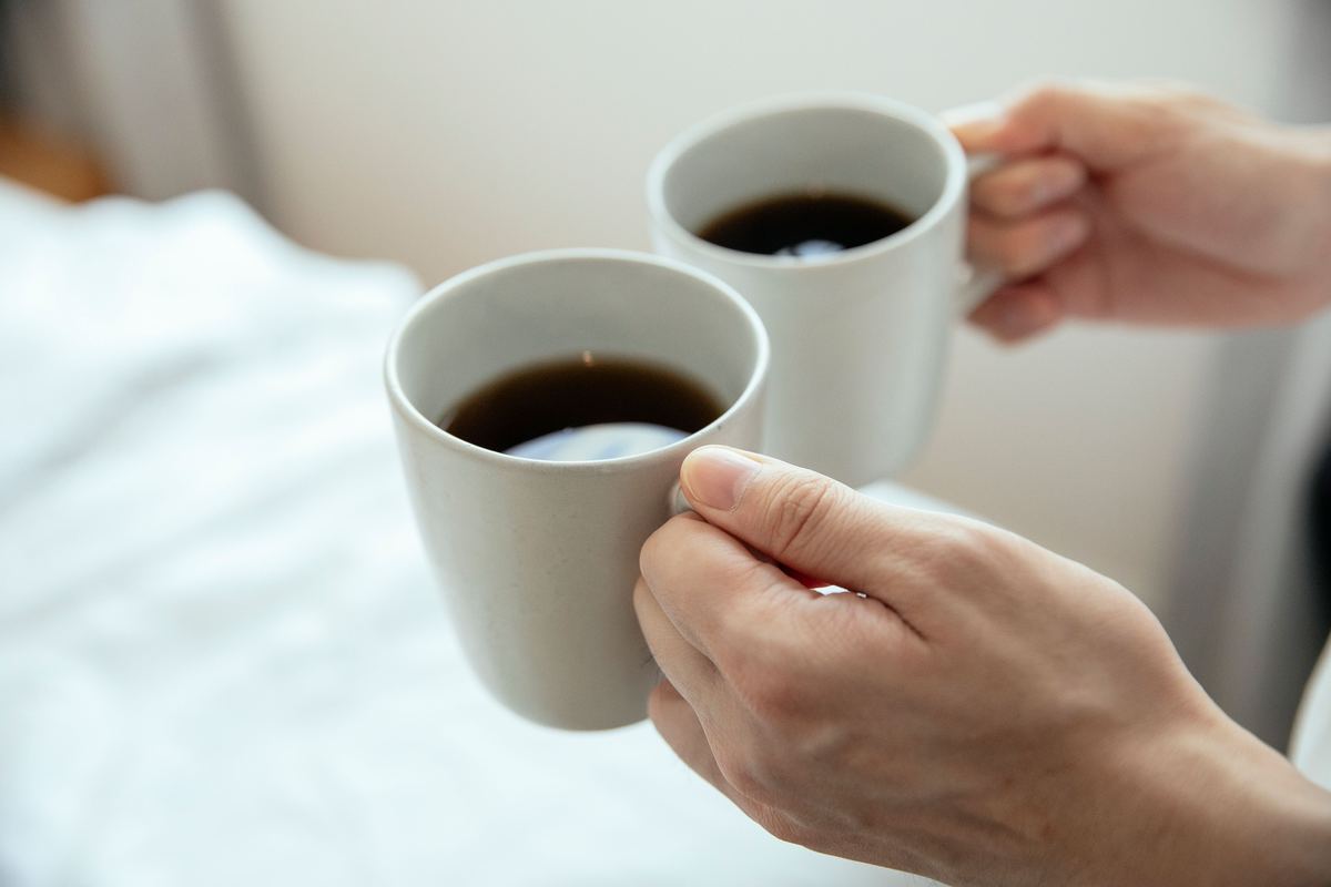 Two hands each holding a mug of coffee