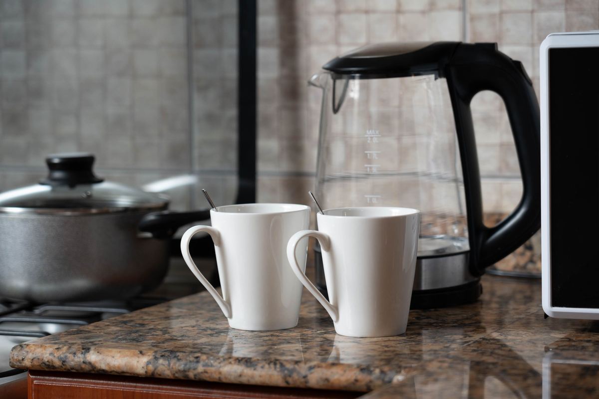 Two mugs on a kitchen counter beside a kettle