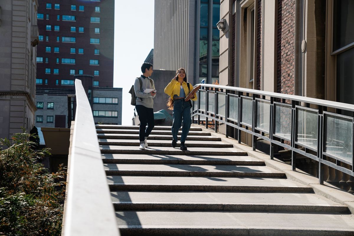 Two students walking down steps on a college campus