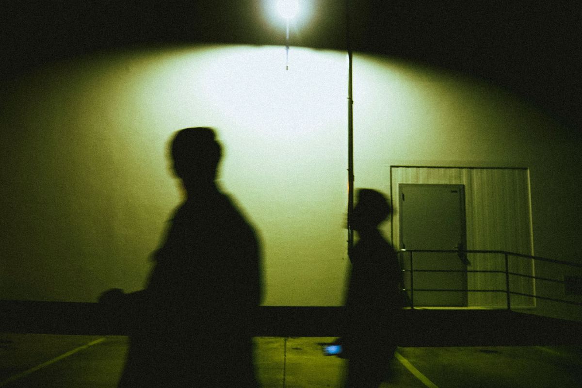 Silhouettes of two people walking under a streetlight at night