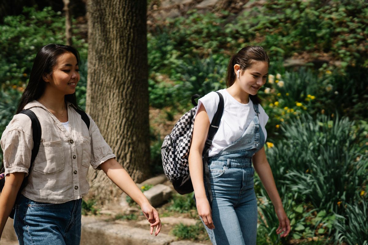 Two teenagers walking outdoors together with backpacks