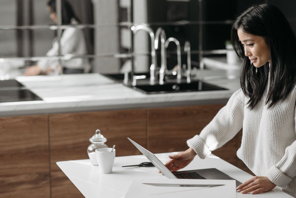 A person working on a laptop at a kitchen counter